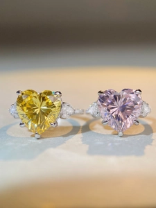 Macro shot of silver heart rings with yellow and pink stones in classic claw setting
