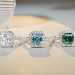 Macro detail of three emerald-cut halo rings in white, blue, and green high carbon stones