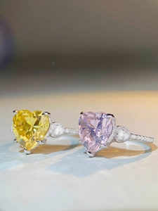 Macro shot of silver heart rings featuring lemon yellow and pale pink gems with side diamonds