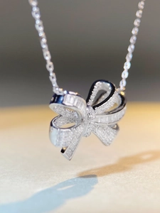 Dettaglio macro del ciondolo a fiocco in argento con pavé di zirconi brillanti