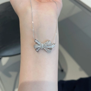Detail of S925 sterling silver bowknot necklace with zircon stones on female arm
