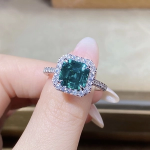 Macro shot of an emerald-cut green stone ring with halo micro-pave diamond setting