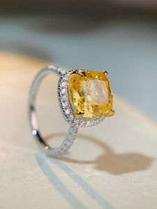 Gros plan sur bague en pierre jaune taille coussin avec halo de diamants et anneau argent