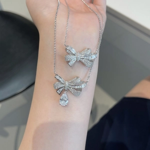 Detail of silver bow pendant necklaces with pear-cut drop stones on a delicate chain