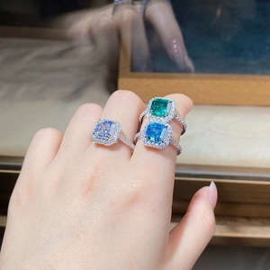 Detailed view of three halo-set square cut rings with vibrant colored center stones
