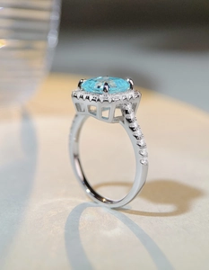 Macro detail of square cut blue gemstone ring with halo diamonds and silver setting