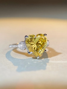 Macro shot of heart-shaped yellow gemstone ring with pavé diamonds on a silver band
