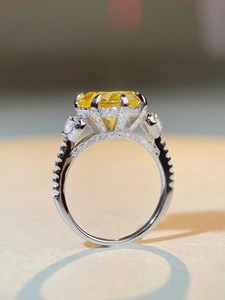 Macro shot of silver heart ring featuring a large yellow gemstone and pavé diamonds