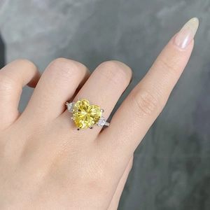 Close-up of heart-shaped yellow diamond ring in silver setting worn on finger