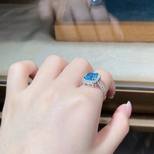 Detail of S925 silver ring featuring a large emerald cut blue stone with halo diamonds
