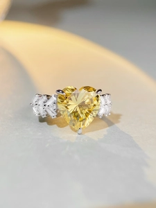 Macro shot of silver ring featuring a large heart-shaped yellow gemstone and side diamonds