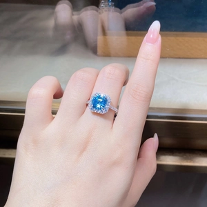 Detailed view of emerald-cut aquamarine zircon ring with luxury halo diamond setting