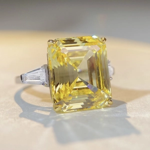 Macro shot of an emerald-cut yellow zircon ring with side baguette diamonds and silver band
