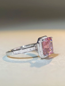 Vue latérale macro d'une bague avec gemme rose rectangulaire et halo en argent