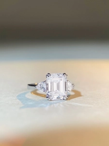 Vue macro d'une pierre centrale taille émeraude et diamants poire sur anneau en argent