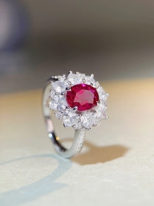 Close-up of oval red gemstone ring with heart-shaped halo and micro-pave silver band