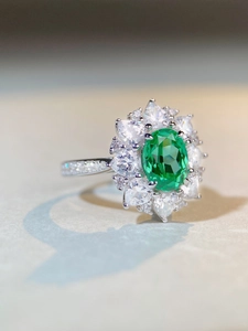 Vue macro d'une bague avec gemme verte ovale, halo en poire et pierres de côté brillantes
