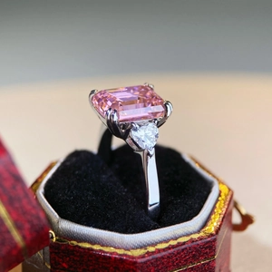 Macro shot of a 4-carat emerald cut pink stone ring with heart side stones in a red jewelry box