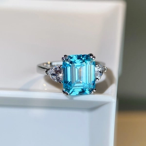 Macro view of three-stone ring with rectangle light blue gem and silver band