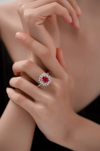 Close-up of a large oval ruby ring with shimmering diamond halo on model's hand