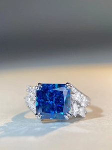 Macro view of blue cushion cut gemstone ring with marquise diamond side clusters