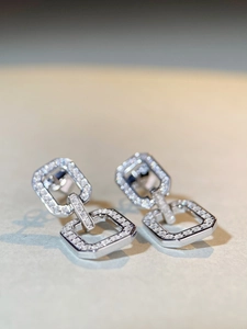 Macro shot of silver S925 earrings with sparkling zircon pave in geometric square link design