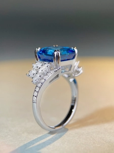 Macro shot of rectangular emerald-cut blue gemstone ring with micro-paved white zircons