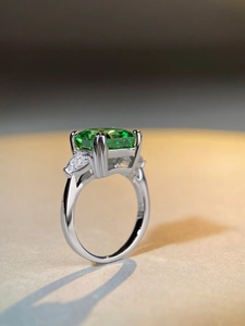 Macro view of emerald-cut green stone ring with pear-shaped side diamonds in silver