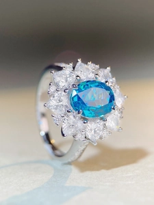 Gros plan sur bague en argent avec aigue-marine ovale et entourage de diamants brillants