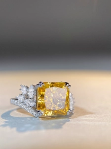Macro view of radiant cut yellow gemstone ring with asymmetrical diamond side clusters