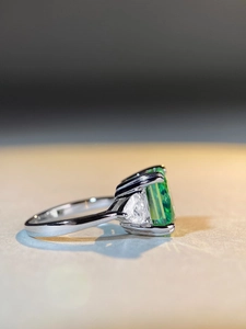 Macro side view of emerald-cut green gemstone with trillion-cut side diamonds on S925 ring