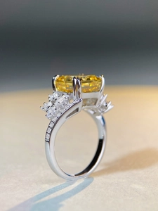 Macro detail of radiant cut yellow gemstone ring with silver band and side stones