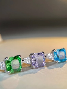 Macro shot of 925 silver rings featuring radiant cut green, purple, and blue gemstones