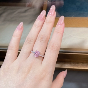 Close-up of radiant cut pink diamond ring in silver setting worn on woman's hand
