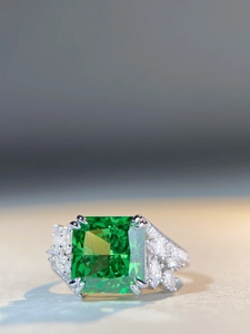 Macro shot of emerald green square-cut gemstone and marquise side stones on silver ring