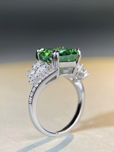 Macro side view of rectangular emerald-cut green stone ring with zircon accent side stones