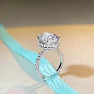 Macro detail of a 10ct radiant cut silver ring with a halo setting on blue silk