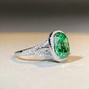 Macro side view of cushion-cut green gemstone ring with pavé-set diamonds on silver band