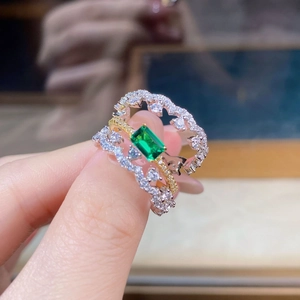 Detailed close-up of a stacked lace ring featuring a green emerald-cut zircon and micro-diamonds