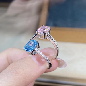 Close-up of radiant cut pink and blue stone rings with pavé set bands on a hand