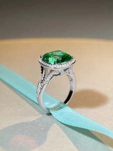 Macro view of S925 silver ring with emerald-cut Paraiba green stone on blue silk