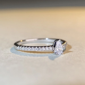 Pear cut moissanite ring in 925 sterling silver with a half-eternity pavé band