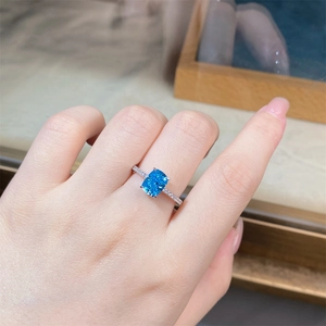 Detailed view of radiant cut aquamarine silver ring with pave set side diamonds on finger