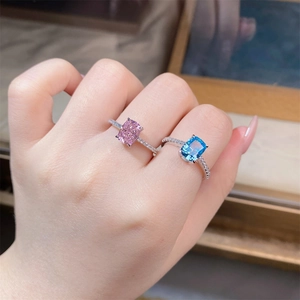 Close-up of cushion-cut pink and blue silver rings with side stones on a finger