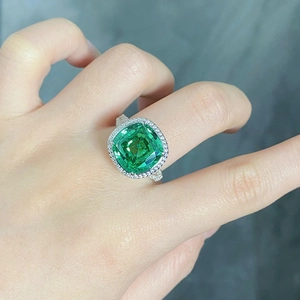 Macro shot of cushion-cut green gemstone ring with halo diamonds on S925 silver band