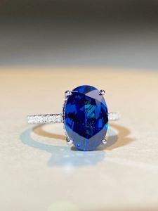 Macro shot of large oval-cut blue sapphire ring with a diamond-paved silver-white band