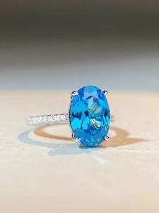 Macro detail of oval aquamarine gemstone ring with micro-pave diamond band in silver
