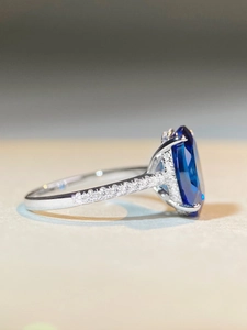 Macro side view of 925 silver ring featuring a large oval blue sapphire and pavé diamonds