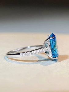 Detailed side view of silver ring featuring oval blue gemstone and pavé settings