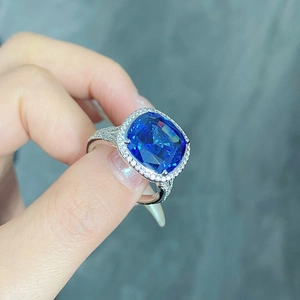 Gros plan d'une bague avec saphir bleu taille coussin et diamants entourés